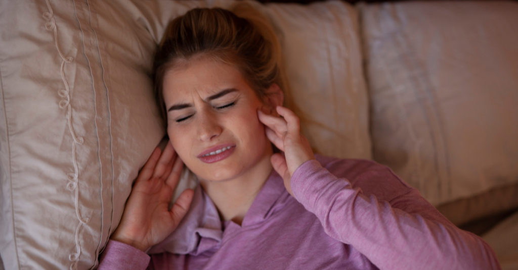 woman experiencing TMJ symptoms of jaw pain in the morning.